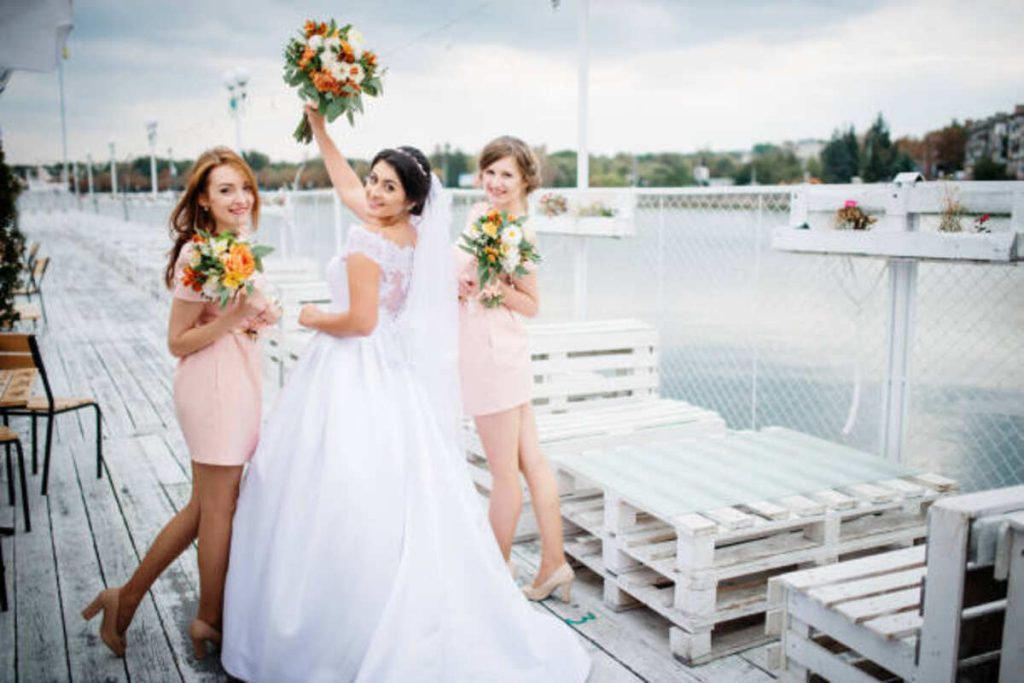 bride with bridesmaids posed on the pier berth at cloudy wedding day